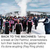 BACK TO THE MACHINES: Taking a break at Old Faithful,
snowmobilers turn their backs to the geyser before it's done
erupting